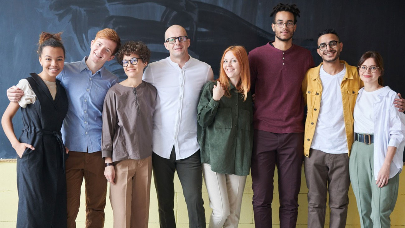 Seven people standing together in a group smiling at the camera