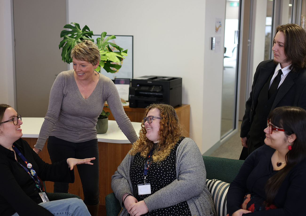 Five members of the EmpowerED team chatting together, two standing and three sitting
